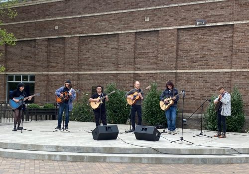 Guitar ensemble performing in front of Brown Hall